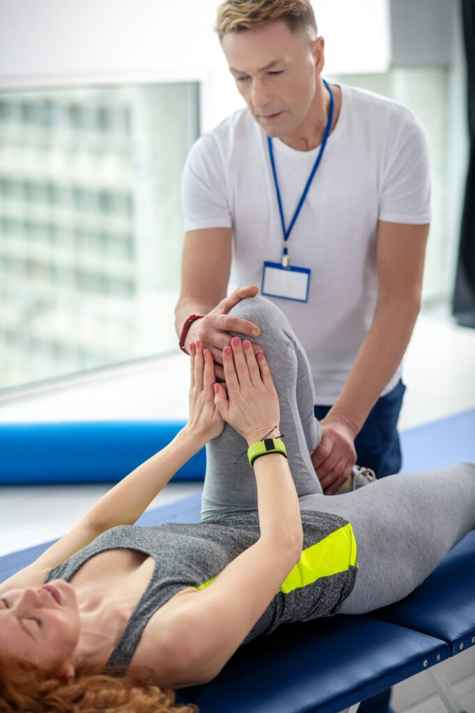 Male physiotherapist treating knee injury of female patient